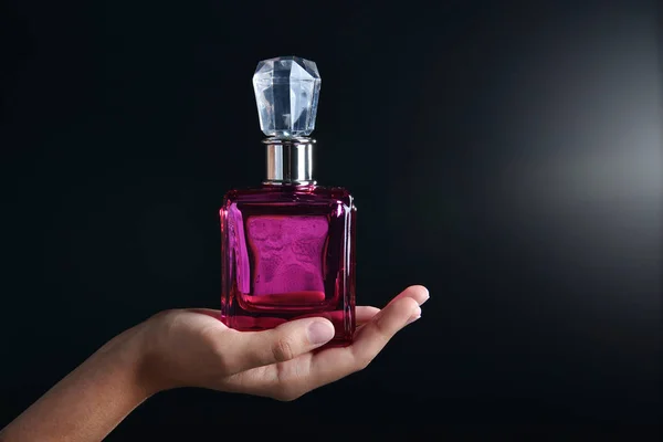 Female hand with bottle of perfume on dark background — Stock Photo, Image