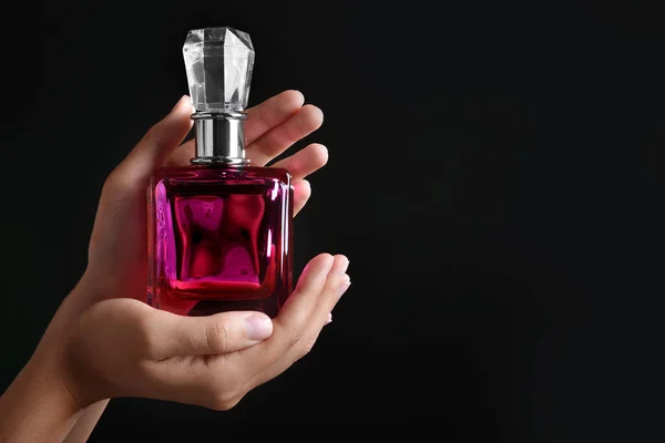 Female hands with bottle of perfume on dark background — Stock Photo, Image