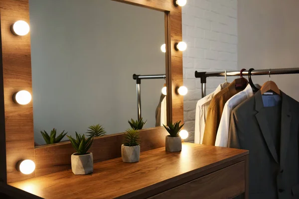 Tavolo con specchio e vestiti maschili in camerino moderno — Foto Stock