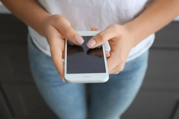 Young woman using modern mobile phone at home, closeup — Stock Photo, Image