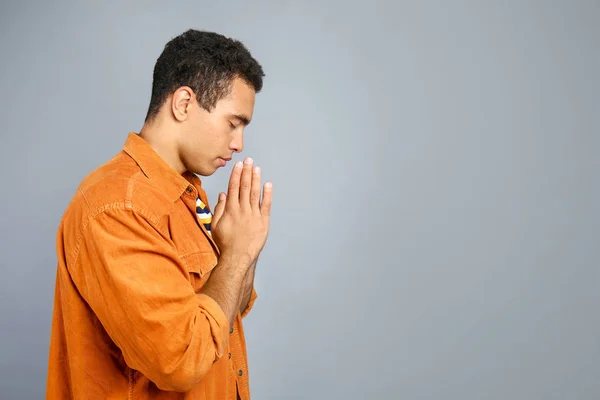 Jonge Afro-Amerikaanse man bidden op grijze achtergrond — Stockfoto