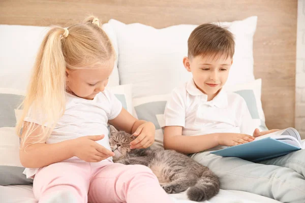 Little children with cute cat in bedroom — Stock Photo, Image