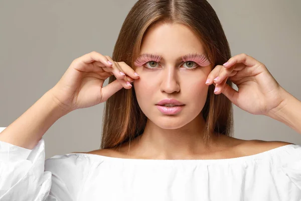 Young woman with creative eyelashes on grey background — Stock Photo, Image