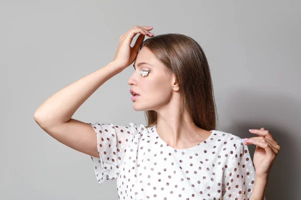 Young woman with creative eyelashes on grey background — Stock Photo, Image