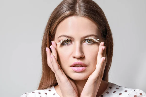 Young woman with creative eyelashes on grey background — Stock Photo, Image