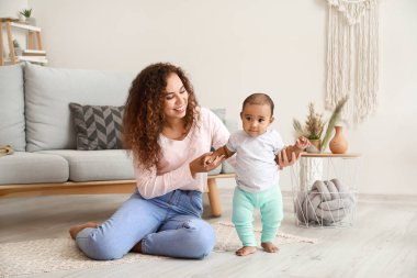 Afro-Amerikalı anne evde yürümek için küçük bebek öğretiyor