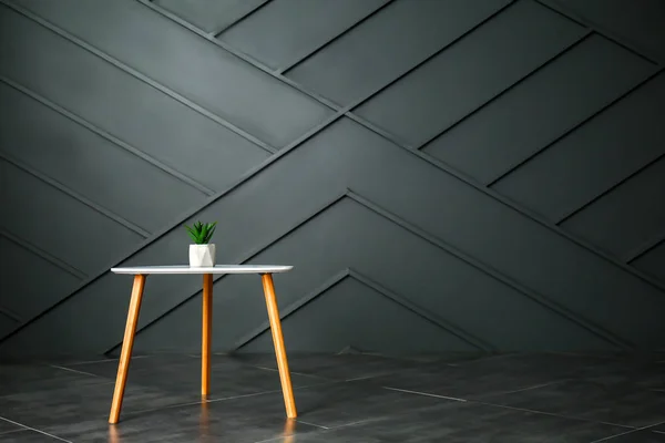 Mesa con planta de interior cerca de la pared oscura — Foto de Stock