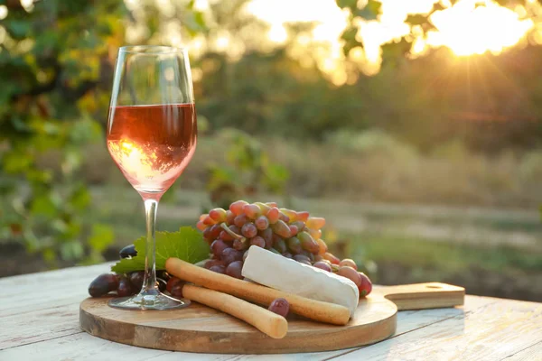 Copo de vinho com lanches na mesa de madeira na vinha — Fotografia de Stock