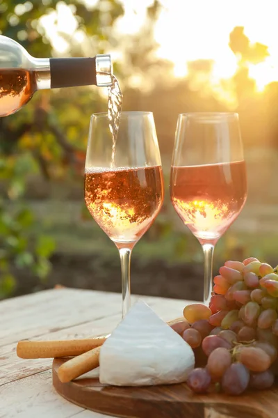 Nalévání chutného vína z láhve do sklenic na stole s občerstvením v vinici — Stock fotografie