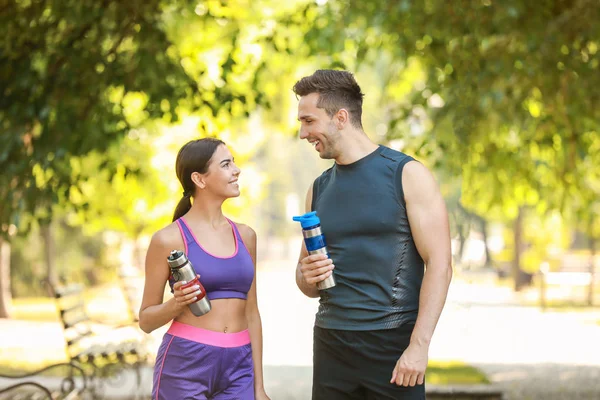 Desportivo jovem casal com garrafas de água no parque — Fotografia de Stock