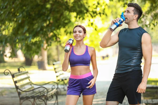 Deportiva joven pareja bebiendo agua en el parque — Foto de Stock