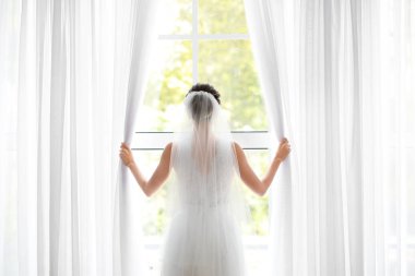 Güzel genç gelin evde düğün töreni öncesi pencerede perdeleri açma, arka görünüm