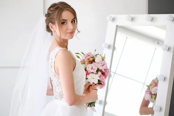 Beautiful young bride with bouquet before wedding ceremony at home — Stock Photo, Image