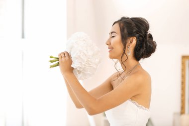 Pencere yakınında çiçek buketi ile güzel genç Asya gelin