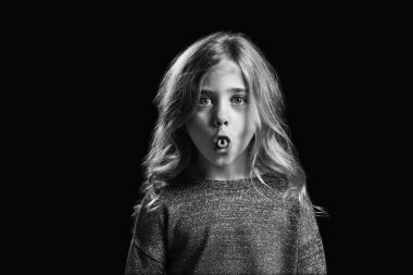 Koyu arka plan üzerinde grimacing küçük kız siyah beyaz portre