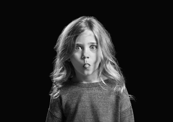 어두운 배경에 얼굴을 찡그리는 어린 소녀의 흑백 초상화 — 스톡 사진
