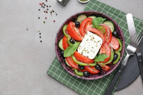 Teller mit leckerem griechischen Salat auf grauem Hintergrund — Stockfoto