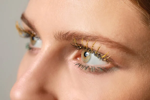 Young woman with creative eyelashes on grey background, closeup — Stock Photo, Image