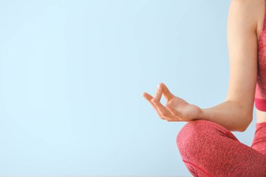 Genç bir kadın renkli arka plan üzerinde meditasyon yapıyor.