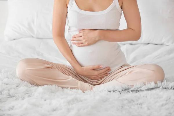 Schöne schwangere Frau sitzt zu Hause auf dem Bett — Stockfoto