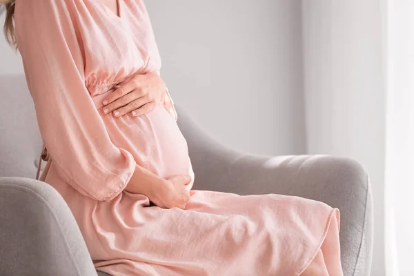 Hermosa mujer embarazada sentada en sillón en casa — Foto de Stock