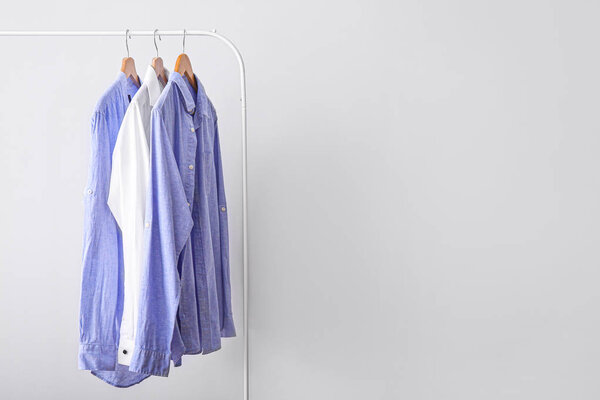 Rack with stylish clothes on light background