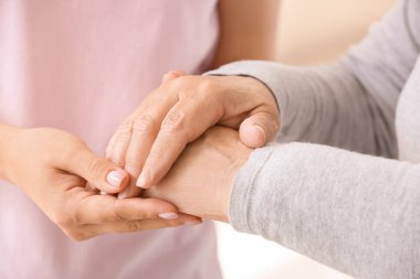 Genç kadın büyükannesinin elini tutuyor, yakın çekim. Bakım ve destek kavramı