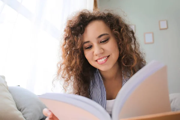 Όμορφη νεαρή γυναίκα διαβάζει βιβλίο στο σπίτι — Φωτογραφία Αρχείου