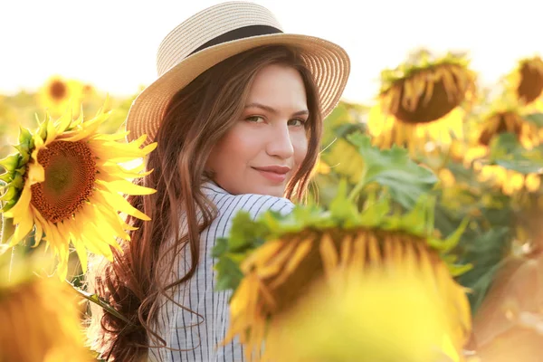 Beautiful young woman in sunflower field on summer day — Stock Photo, Image