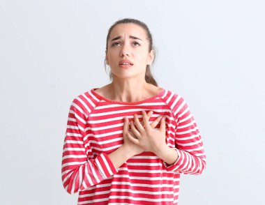 Işık arka plan üzerinde kalp krizi geçiren genç kadın