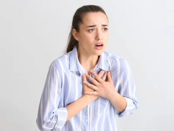 Işık arka plan üzerinde kalp krizi geçiren genç kadın — Stok fotoğraf