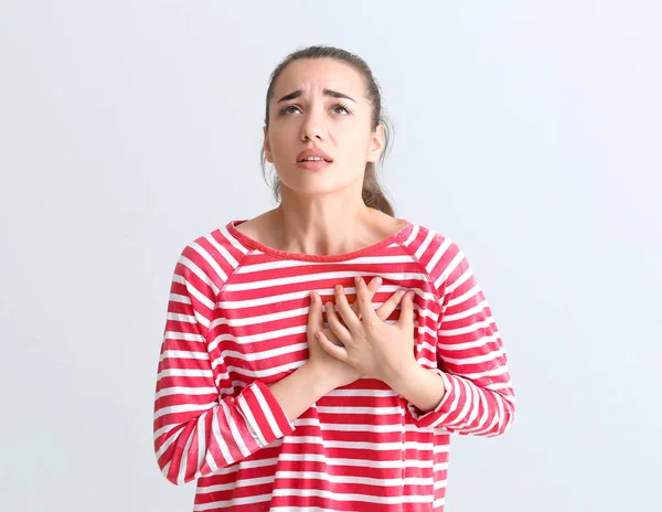 Junge Frau erleidet Herzinfarkt vor hellem Hintergrund — Stockfoto