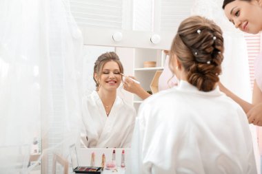 Profesyonel makyöz evde genç gelinle çalışıyor.