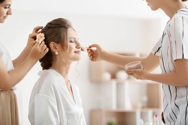 Artista de maquiagem profissional e cabeleireiro trabalhando com a jovem noiva em casa — Fotografia de Stock