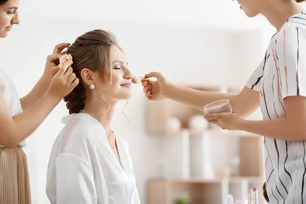 Maquilleuse professionnelle et coiffeuse travaillant avec une jeune mariée à la maison — Photo