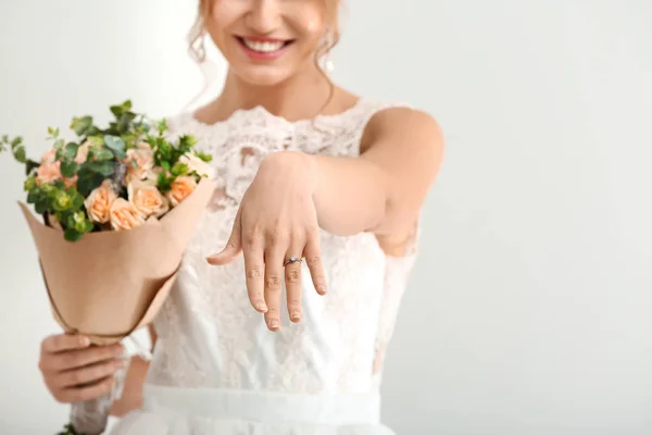 Красива молода наречена з букетом квітів, що показує її обручку на білому тлі — стокове фото