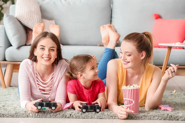 Happy lesbian couple with little daughter playing video game at home — Stock Photo, Image