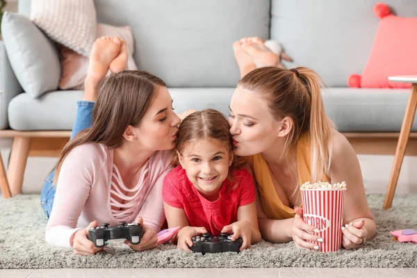 Happy lesbian couple with little daughter playing video game at home — Stock Photo, Image