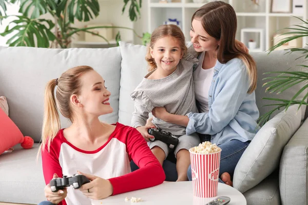 Glückliches lesbisches Paar mit kleiner Tochter beim Videospiel zu Hause — Stockfoto