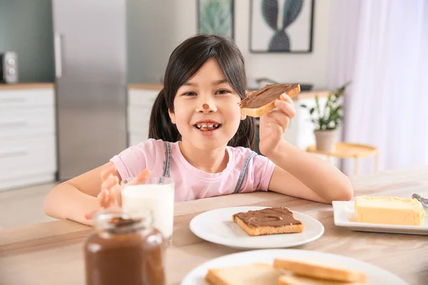 Mutfakta yayılan çikolata ile lezzetli tost yeme komik küçük kız — Stok fotoğraf