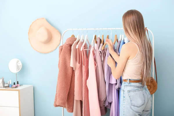 Jonge vrouw kiezen kleren in kleedkamer — Stockfoto