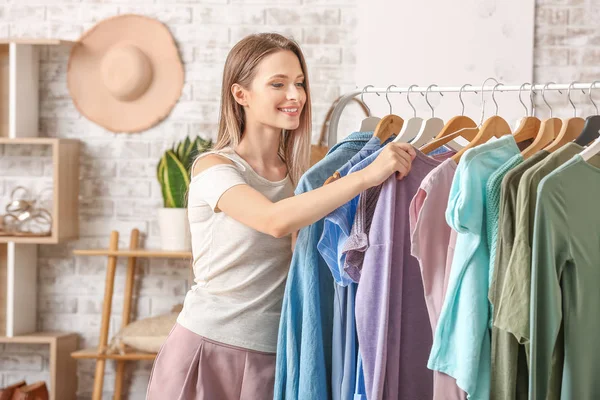 Jonge vrouw kiezen kleren in kleedkamer — Stockfoto