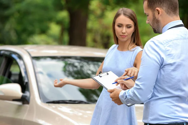 Giovane donna e agente assicurativo vicino danneggiato auto all'aperto — Foto Stock