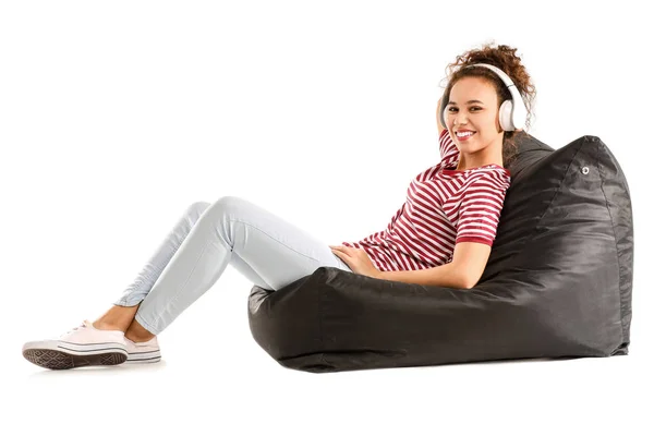 Krásná africko-americká žena poslech hudby při relaxaci na beanbag proti bílému pozadí — Stock fotografie