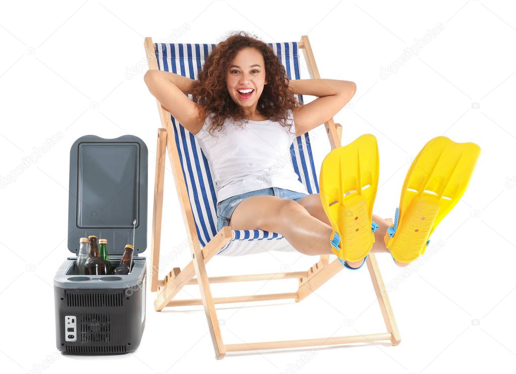 Beautiful African-American woman relaxing on sun lounger against white background