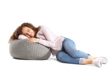 Güzel Afro-Amerikalı kadın beyaz arka planda puf üzerinde dinleniyor.