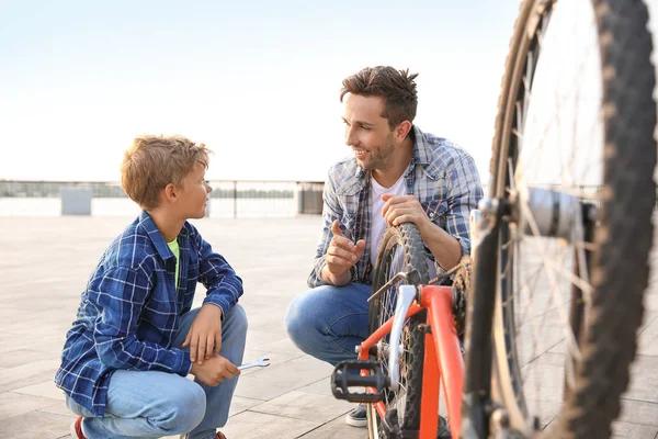 Pai e seu filho reparando bicicleta ao ar livre — Fotografia de Stock