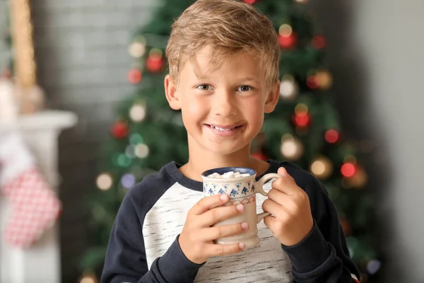 Söt liten pojke dricker varm choklad hemma på julafton — Stockfoto