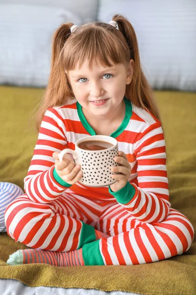 Cute little girl drinking hot chocolate in bedroom — Stock Photo, Image