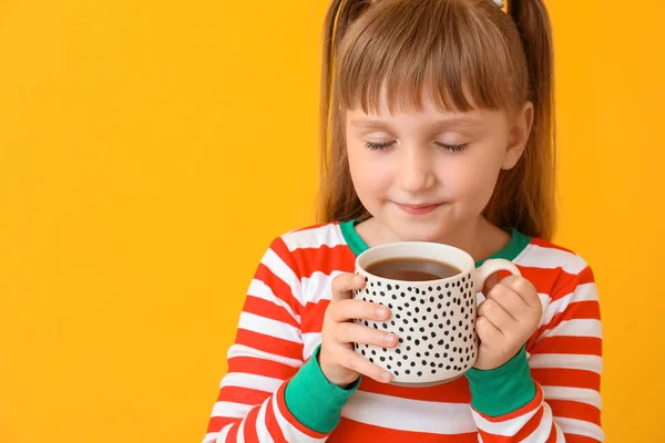 Cute little girl drinking hot chocolate on color background — Stock Photo, Image